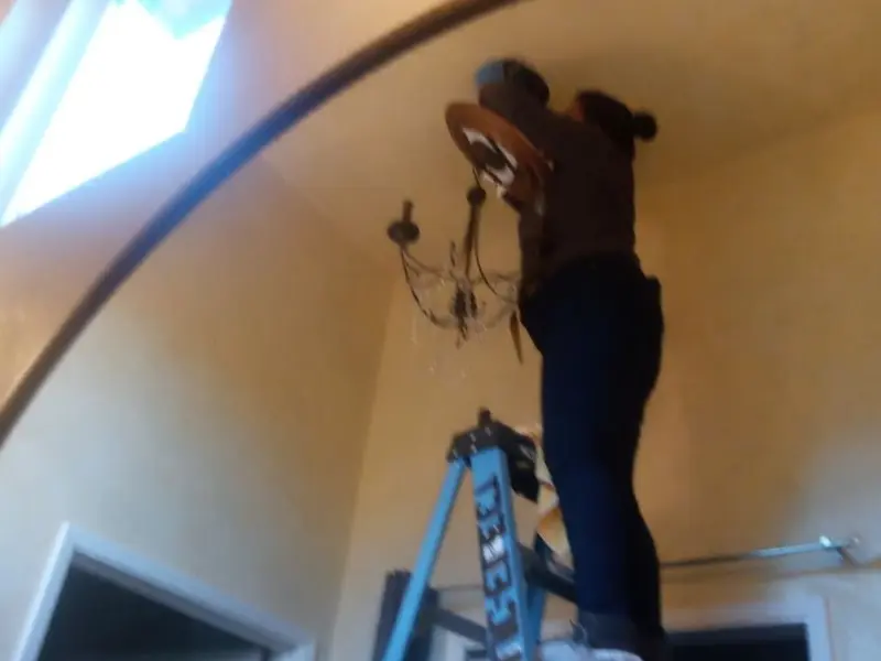 Electrician installing a chandelier in a Vinton residence